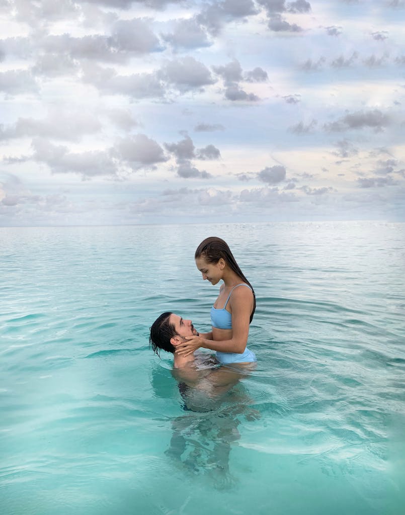 A couple enjoying a playful moment in the crystal-clear waters of the Maldives.