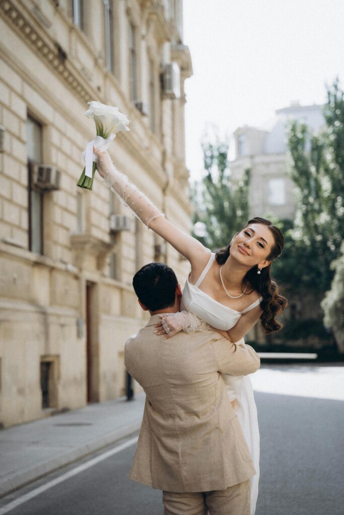 groom lifting bride while walking down stree