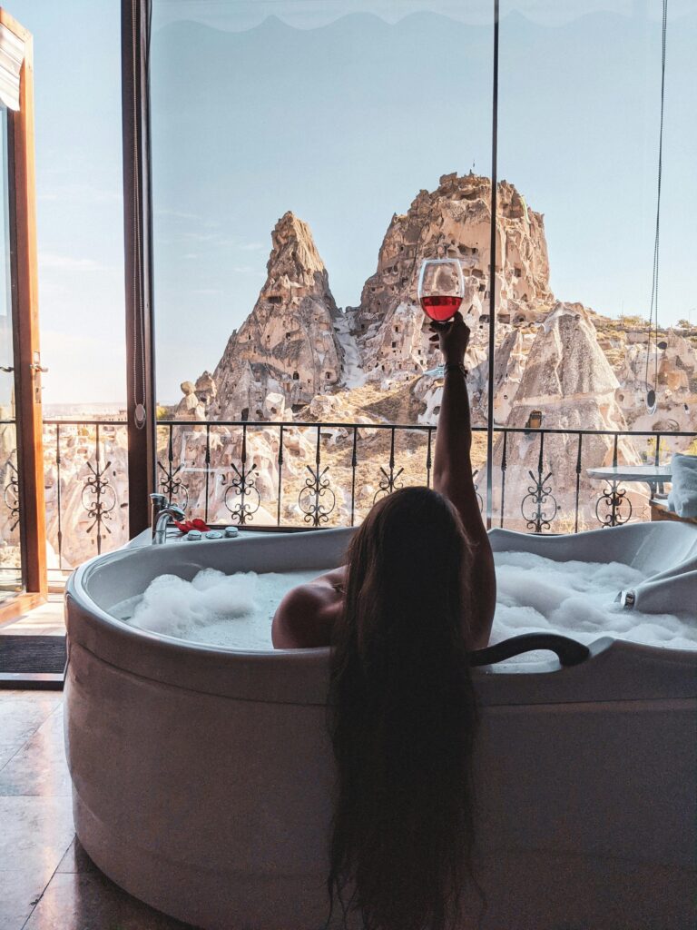 woman drinking wine in jacuzzi tub overlooking mountains