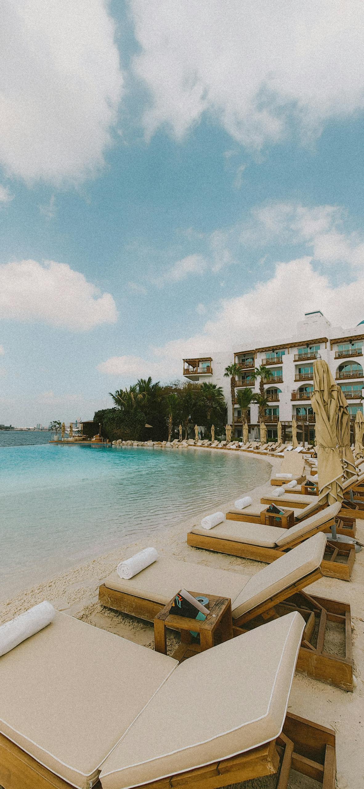 Relaxing beach scene at a luxury resort with sun loungers and clear skies.